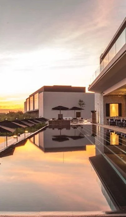 Arquitectura de NIZUC reflejada en una piscina al atardecer.